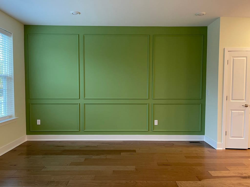 Green painted wall panels with custom molding in a living room